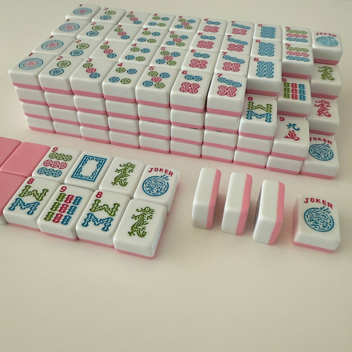 Set of colorful麻将 tiles with jokers on a light pink background
